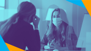 Two women in a meeting, one wearing masks