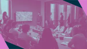 A pink duotone image of a meeting in a boardroom