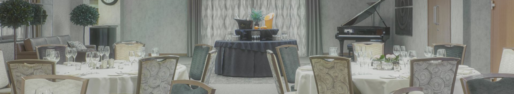 An event space at the Mallory Court Hotel, including several roundtables and a black piano in the back corner