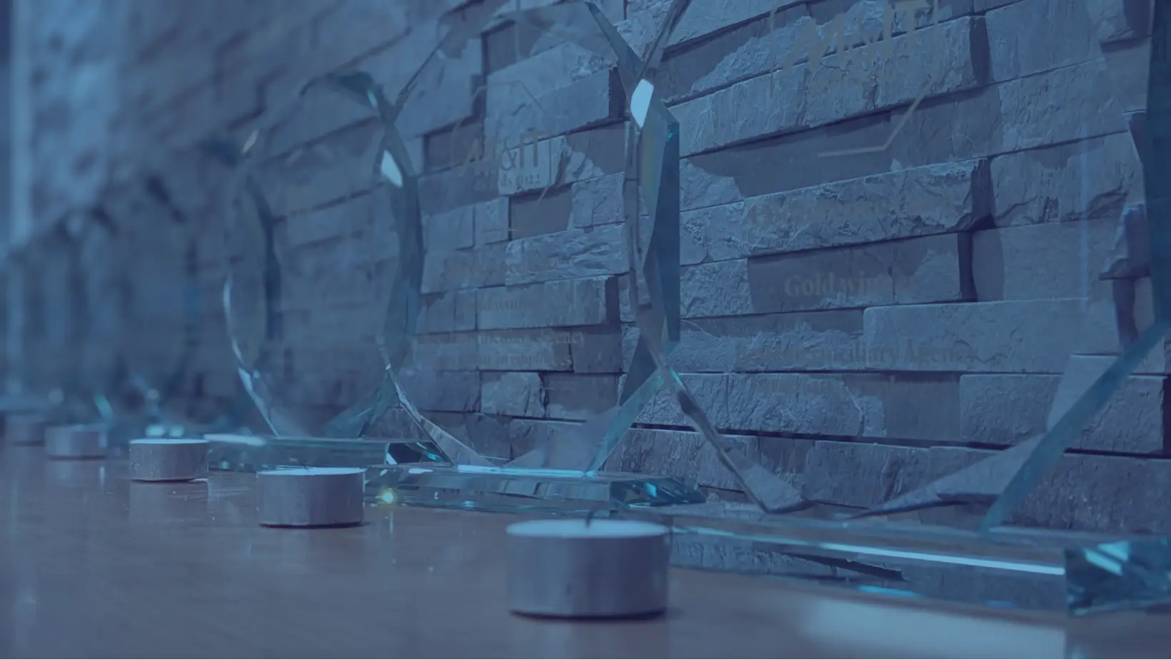 Blue Duotone image of M&IT awards lined on a desk