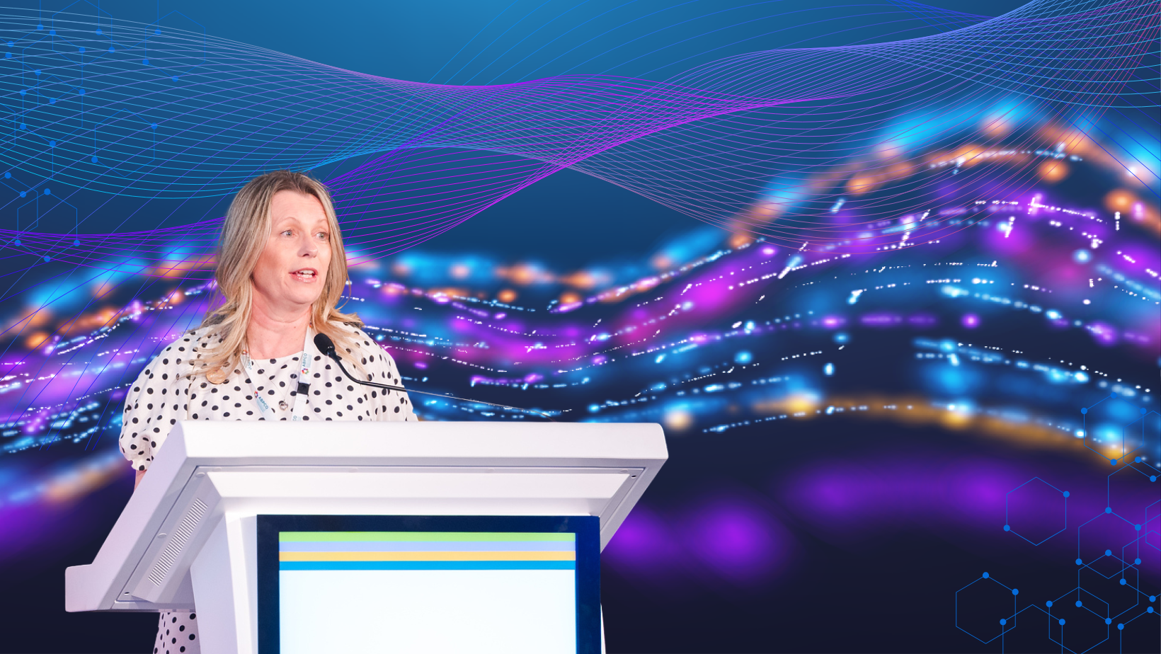 A woman stands behind a pedestal with a microphone in front of an AI background